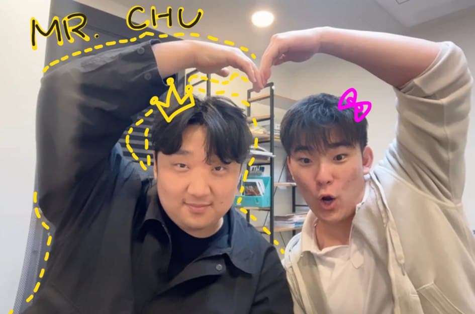 Two students making a heart shape over Mr. Chu, annotated in yellow marker