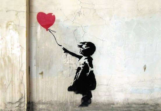 Banksy's Girl with Balloon stencilled on a weathered wall, a red heart-shaped balloon drifting from her hand