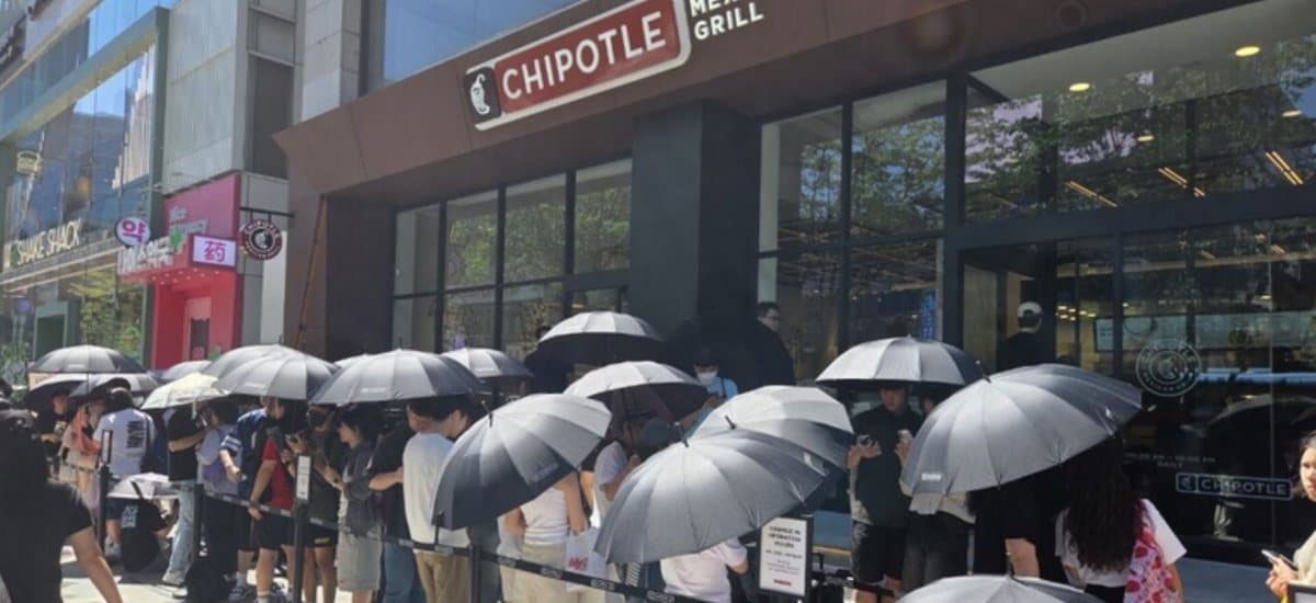 A line of people under black umbrellas outside the new Chipotle in Gangnam