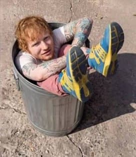 Ed Sheeran sitting folded up inside a metal trash can
