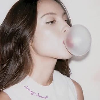 A young woman blowing a large bubblegum bubble